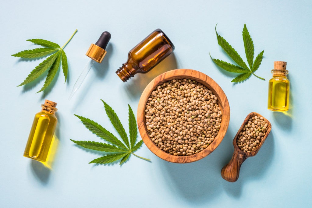 Cannabis oil hemp oil with cannabis seeds and cannabis leaves at blue background. Top view with copy space.